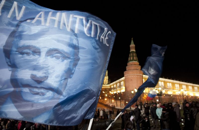 Partidário balança uma bandeira com o rosto de Putin | AFP