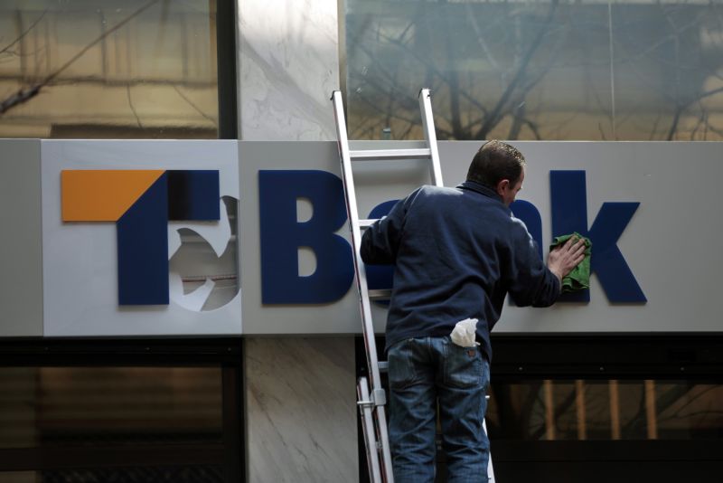 Funcionário limpa fachada de banco em Atenas: instituições terão perdas com seus títulos gregos, por bem ou por mal | YannisBehrakis/Reuters