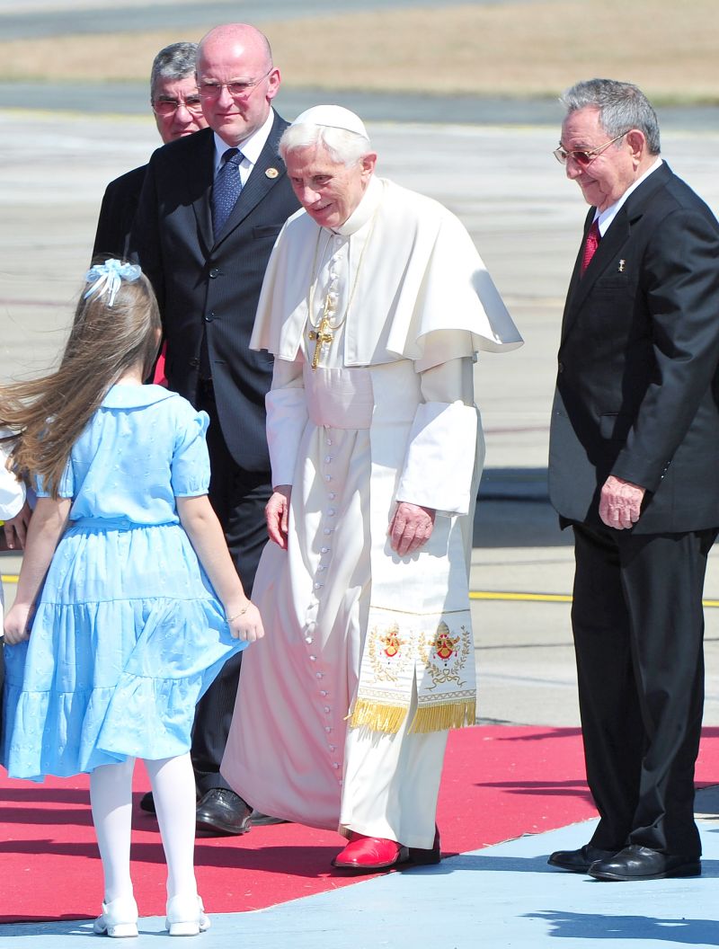 Acompanhado do presidente Raúl Castro (direita), Bento XVI é recebido por criança em Santiago de Cuba | Alberto Pizzoli/AFP