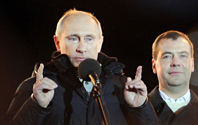 Com lágrimas nos olhos e ao lado do atual presidente Dmitry Medvedev, primeiro-ministro russo Vladimir Putin (esq.), acena para seus eleitores durante o pleito na praça Manezhnaya, em Moscou | Natalia Kolesnikova/AFP