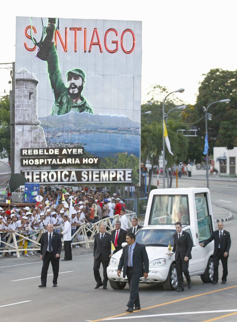 Bento XVI passa diante de painel com foto de Fidel e a mensagem rebelde ontem, hospitaleira hoje, heroica sempre | Carlos Garcia Rawlins/Reuters