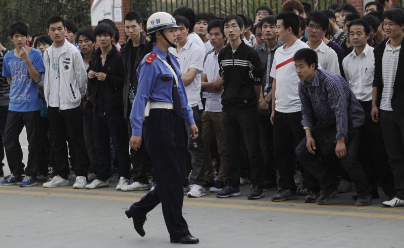 Policial controla fila de candidatos a vagas na Foxconn: empresa vai reduzir carga horária dos empregados | Reuters