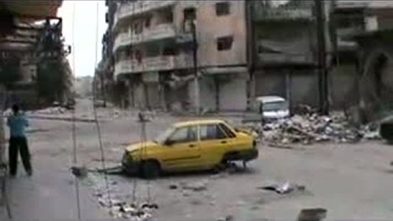 Imagem tirada de um vídeo enviado no Youtube em 08 de abril de 2012, mostra um homem caminhando ao longo das casas e carros danificados, depois de supostamente bombardeios pelo Governo sírio na cidade de Homs | AFP PHOTO/YOUTUBE