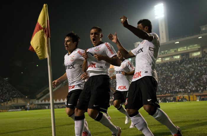 Fábio Santos (centro) comemora com Willian e Paulinho o primeiro gol corintiano contra o Emelec no Pacaembu | Yasuyoshi Chiba/AFP