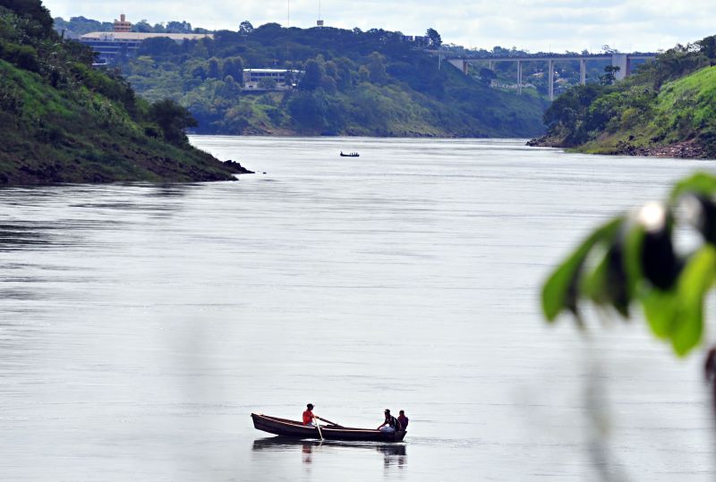 Com a Ponte da Amizade ao fundo, embarcação cruza livremente o Rio Paraná: paraguaias estão entrando no Brasil de barco e levadas para a Espanha, via Foz do Iguaçu | Marcos Labanca/Gazeta do Povo