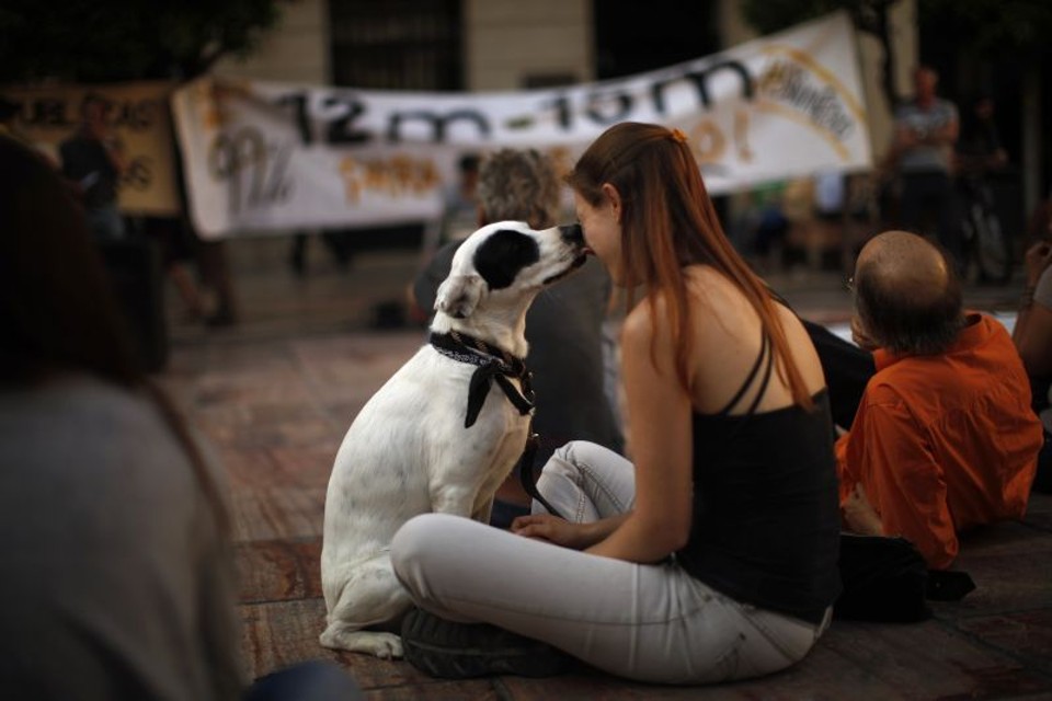 Jovem espanhola recebe apoio de seu cão, em meio aos protestos contra a austeridade, em Málaga | Jon Nazca/ Reuters