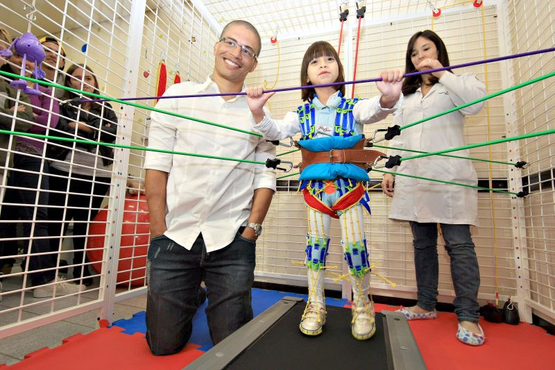 Maria Clara mostra ao jogador de futebol Alex como o macacão a ajuda a caminhar | Ivonaldo Alexandre/ Gazeta do Povo