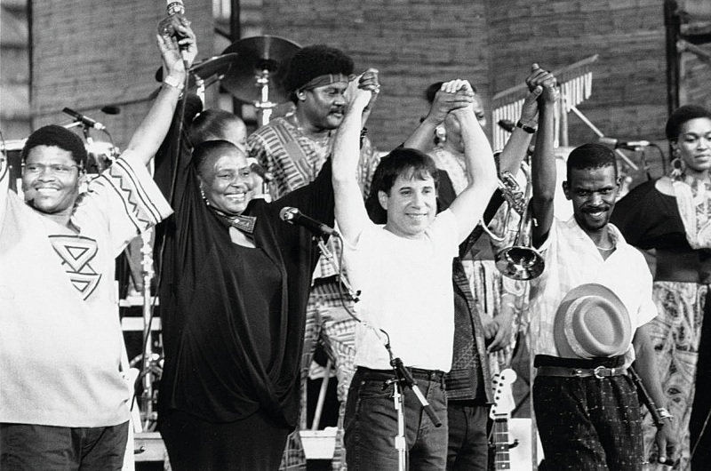 Paul Simon, durante a turnê de Graceland, ao lado de artistas africanos, como a cantora Mirimam Makeba e o guitarrista Ray Phiri (à dir) | Divulgação