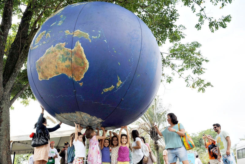 Crianças brincam com globo na Cúpula dos Povos, evento que faz parte da conferência | Vaanderlei Almeida / AFP