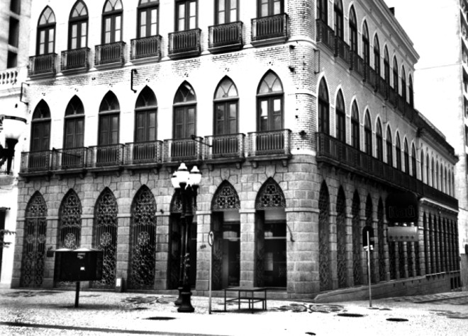 Nessa esquina, Rua XV com Monsenhor, tem uma casa sem janelas. Ela foi construída no século 19 pelo português Manoel da Costa Cunha, cuja loja foi saqueada pelos gaúchos na revolução de 1894. A casa não tem janelas, em compensação tem 64 portas. Ali, funcionou o Banestado |