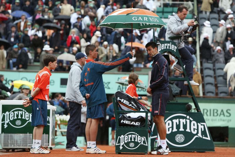 Djokovic se protege da chuva. Final de Roland Garros ficou para segunda-feira | AFP