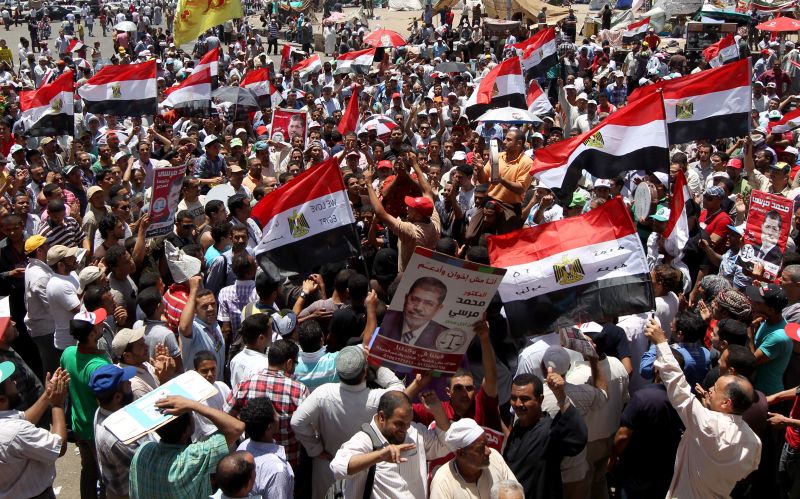 Manifestantes que apoiam a Irmandade Muçulmana seguram retratos do candidato à presidência Mohammed Morsi durante protesto no Cairo | AFP PHOTO/MARWAN NAAMANI