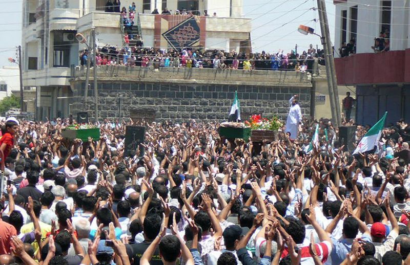 Imagem de quinta-feira mostra funeral de dezenas de mortos em confrontos na província de Daraa, na Síria | AFP PHOTO/LCC SYRIA TOPSHOTS