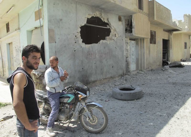 Moradores de Homs, na Síria, observam buraco em parede aberto após ataques à cidade | David Manyua/ONU/Reuters