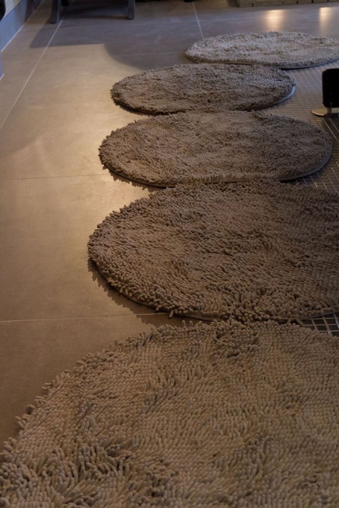 Diversos tapetes de banheiro fora unidos para compor um ambiente na sala |