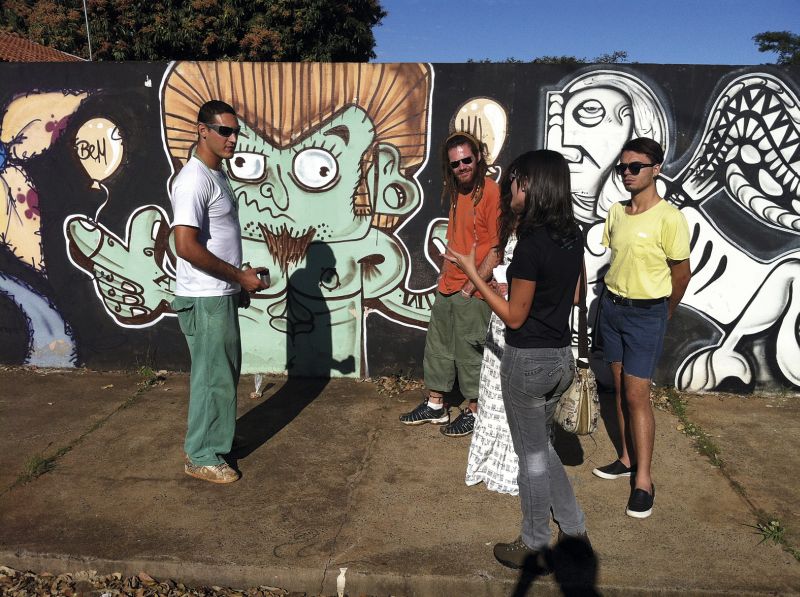 Guto Silva (à esq.) explica ao grupo seu próprio grafite, inspirado no livro Eram os Deuses Astronautas? | Luis Corvini/Divulgação