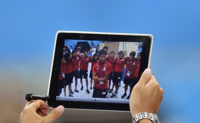 Membro da delegação japonesa usa um iPad para fotografar nadadores do país em Londres | 