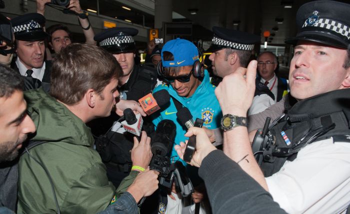 Protegido por policiais, Neymar foi cercado pela imprensa no desembarque brasileiro em Londres | Will Oliver/AFP