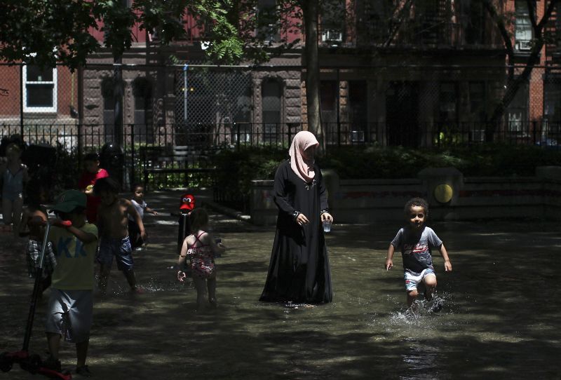 Mulher brinca com criança na água em parque de Nova York. Temperaturas começam a diminuir depois de onda de calor que atingiu o meio-oeste e a costa leste dos Estados Unidos | REUTERS/Shannon Stapleton