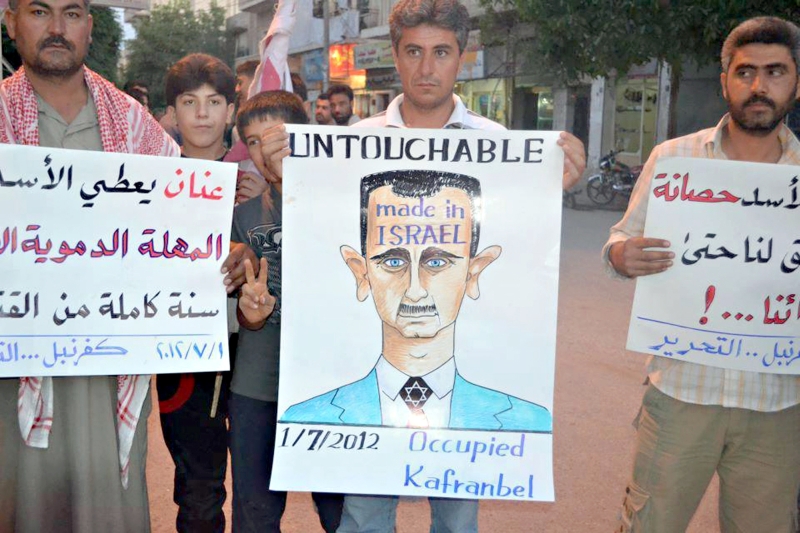 Manifestante sírio exibe caricatura de Assad durante protesto | AFP