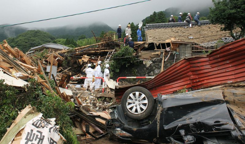 Policiais procuram desaparecidos embaixo dos escombros dae casas que desabaram por causa das chuvas em Kumamoto, no Japão | REUTERS/Kyodo