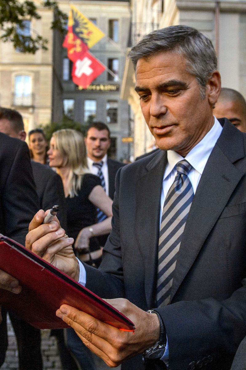 O ator George Clooney assina autógrafos durante evento pró-Obama em Genebra | AFP PHOTO / FABRICE COFFRINI