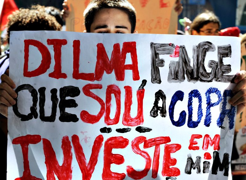 Impedidos de entrar com faixas e camisetas de protesto no local da cerimônia, manifestantes improvisaram cartazes | Antônio Scorza/AFP