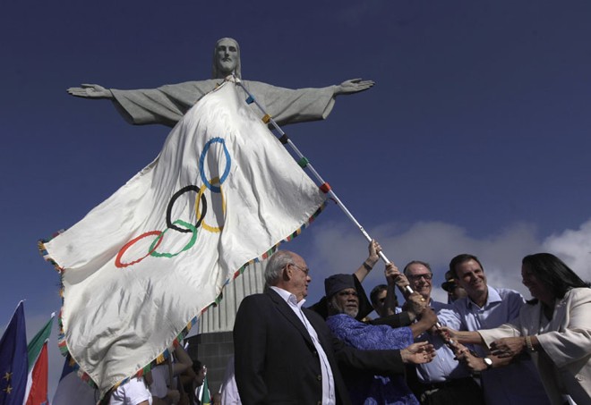 Prefeito do Rio, Eduardo Paes, e autoridades da cidade e do comitê olímpico seguram bandeira durante cerimônia ecumênica em frente do Cristo Redentor |