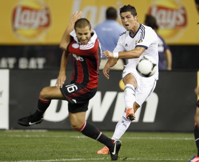 Cristiano Ronaldo chuta para o gol e Flamini, do Milan, tenta se proteger | Adam Hunger / Reuters