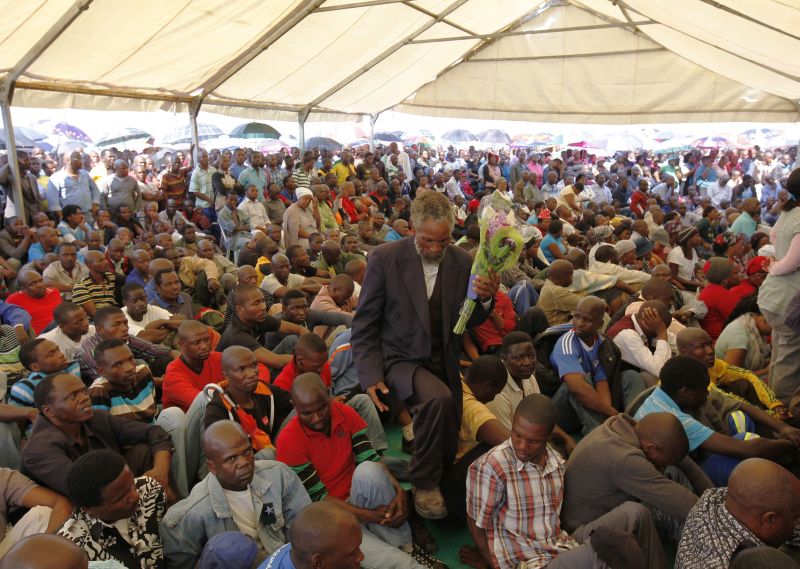 Homem carrega flores durante a homenagem aos mortos do massacre policial na mina de Marikana | Reuters/Siphiwe Sibeko