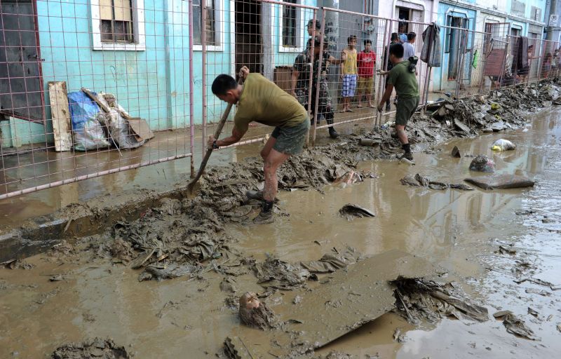 Membros do exército filipino ajudam os moradores dos subúrbios de Manila a limpar as ruas e casas após as inundações | AFP Photo/Jay Directo