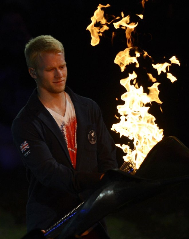 Jonnie Peacock , medalha de ouro no atletismo, com a pira olímpica | 