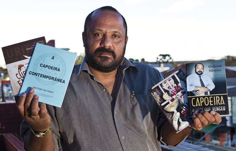 Apesar de odiar posar para fotografias, Silveira mostra os três livros de sua autoria e outro que traz capítulo dedicado a ele | Antônio Costa/Gazeta do Povo