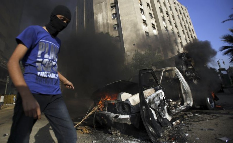 Manifestante passa por veículo destruído em uma das ruas que levam à embaixada dos EUA no Cairo, Egito | Reuters/Amr Abdallah Dalsh