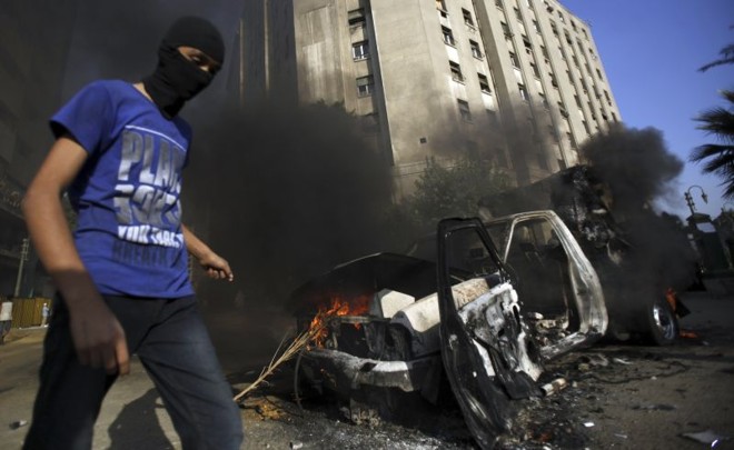 Manifestante passa por veículo destruído em uma das ruas que levam à embaixada dos EUA no Cairo, Egito | Reuters/Amr Abdallah Dalsh