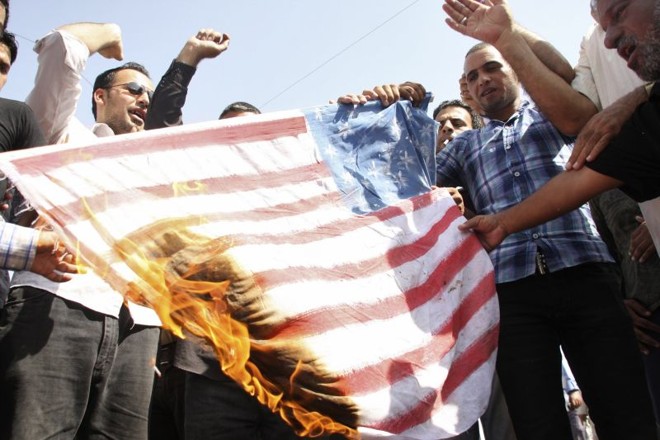 Manifestantes queimam a bandeira americana na cidade de Sadr, que fica a nordeste de Bagdá | Reuters/Wissm al-Okili