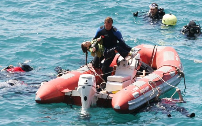 Membro do time de resgate retira criança da água após o naufrágio de uma embarcação com imigrantes ilegais na costa da Turquia | AFP Photo/Ihlas News Agency