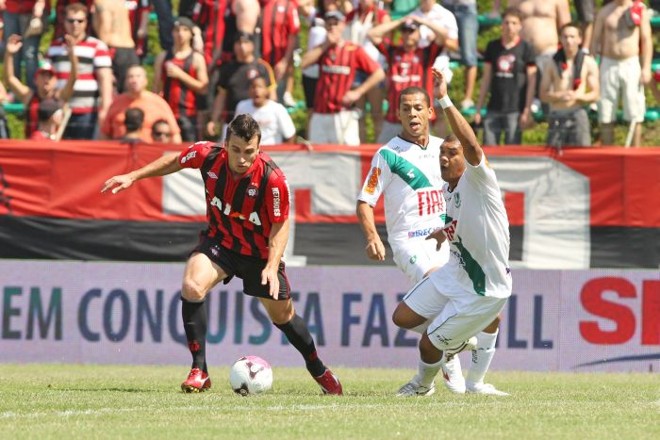 O meia atleticano Elias tenta se livrar da marcação | 