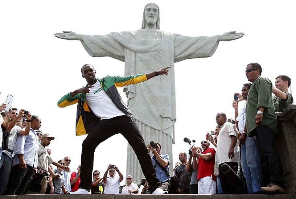 Bolt faz a festa dos turistas em visita ao Cristo Redentor Bolt faz a tradicional pose de relâmpago diante do Cristo Redentor | Reuters