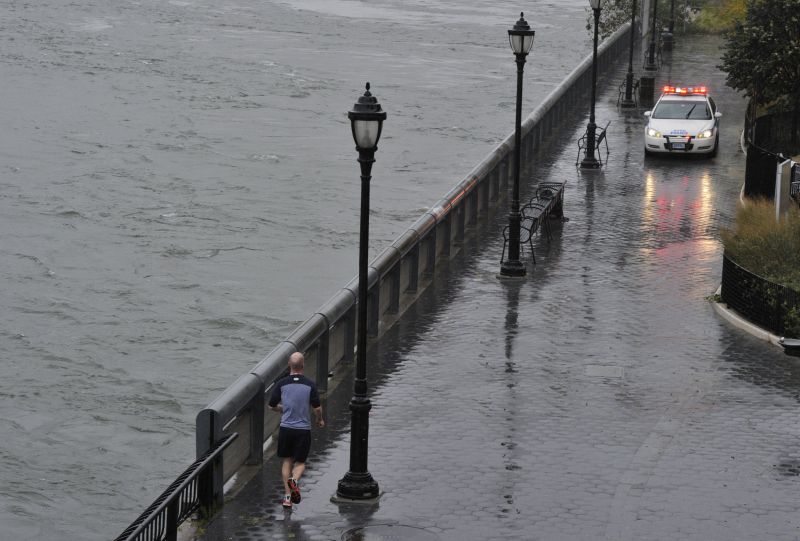 Homem corre enquanto um carro de polícia interdita rua em Nova York | TIMOTHY A. CLARY/ AFP