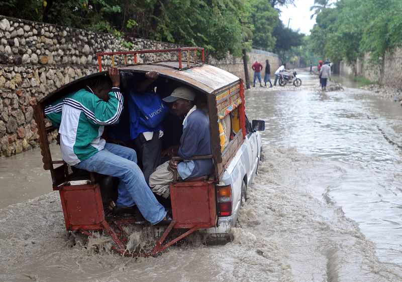 Haitianos em rua alagada após a passagem do furacão Sandy | Thony Belizaire/ AFP