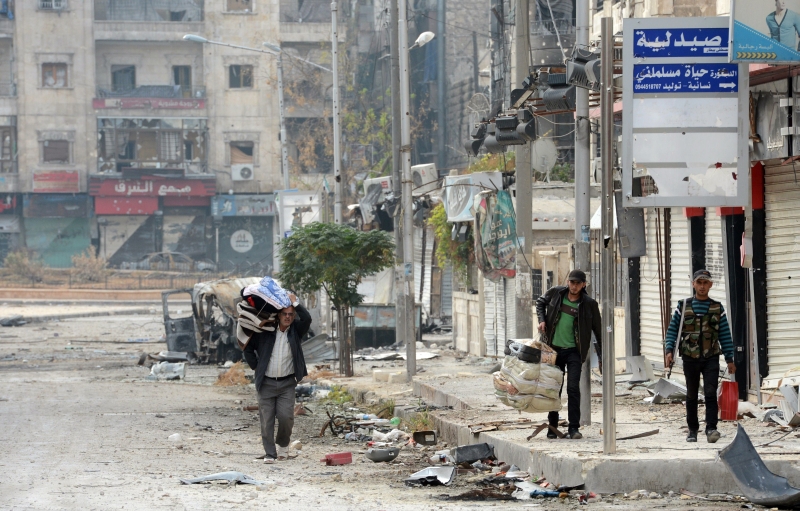 Dois civis são escoltados por rebelde em rua da cidade de Alepo, onde forças do governo e da oposição travam combates | Philippe Desmazes/AFP