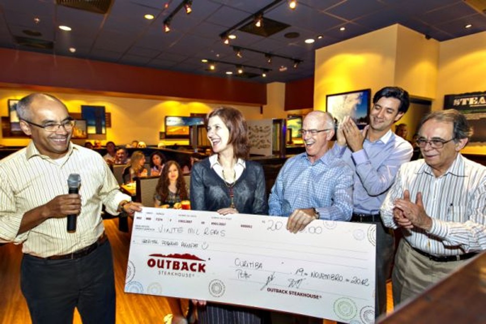 A diretora executiva do Hospital Pequeno Príncipe, Ety Cristina Forte Carneiro, recebeu um cheque simbólico de R$ 20 mil na abertura da segunda unidade do restaurante Outback Steakhouse em Curitiba, no ParkShoppingBarigüi. Acompanhada do hematologista Eurípedes Ferreira (último à dir.), ela recebeu a doação das mãos do CEO da rede, Peter Rodenbeck (de camisa xadrez), de Naldo Barbosa (com o microfone na mão) e Wagner Villaverde (ao fundo), sócios regionais | Diego Pisante