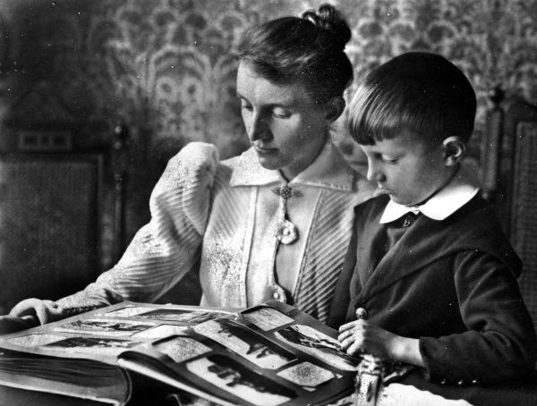 Imagem de mãe e filho folheando álbum fotográfico da família Strobel. Foto de 1907 | Arquivo Cid Destefani