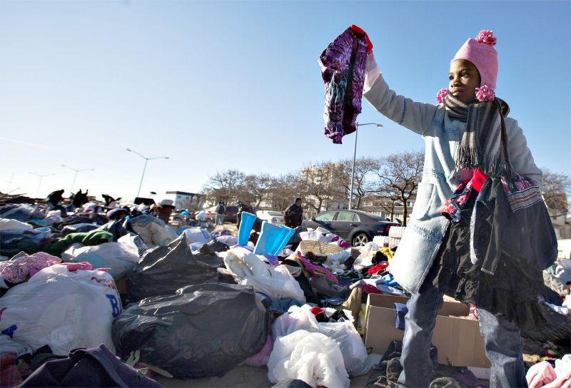 Menina ajuda sua família a vasculhar roupas entre as doações feitas para as vítimas da tempestade Sandy em Nova York | Lucas Jackson/Reuters