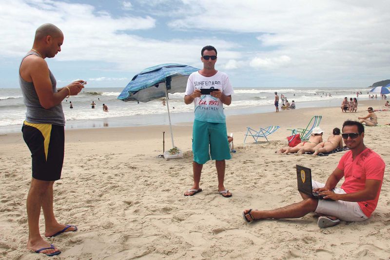 O vendedor Renato Locatelli (no centro) e os amigos não abriram mão de acessar a web na praia | Walter Alves/Gazeta do Povo