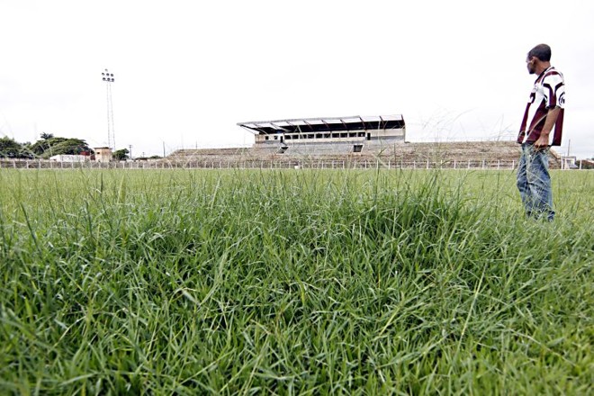 Vista geral do estádio mostra o gramado alto, a cobertura destelhada e alguns dos refletores, que não funcionam porque a fiação foi roubada. |