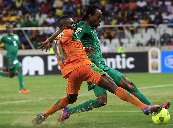 Felix Katongo, de Zâmbia (laranja), divide a bola com Bakary, de Burkina Faso (verde), que se classificou às oitavas da Copa Africana | Reuters