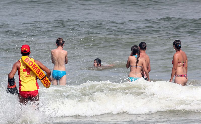 Veranistas aproveitam o mar em Caiobá, observados por um salva-vidas: qualidade da água não afasta os banhistas | Walter Alves/Gazeta do Povo