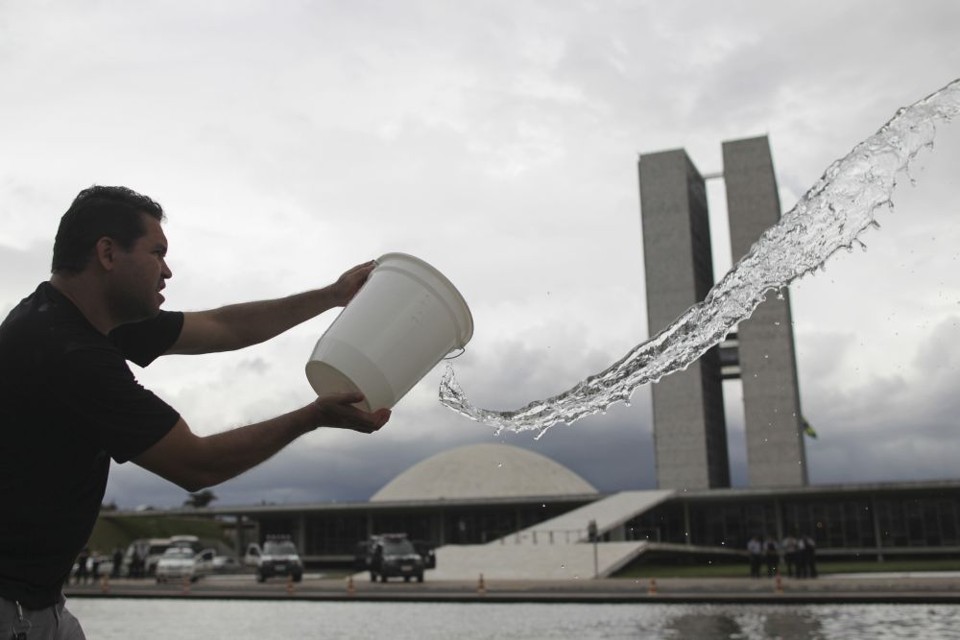 Manifestante joga balde de água para protestar contra a proibição da lavagem da rampa do Congresso | Reuters/Ueslei Marcelino